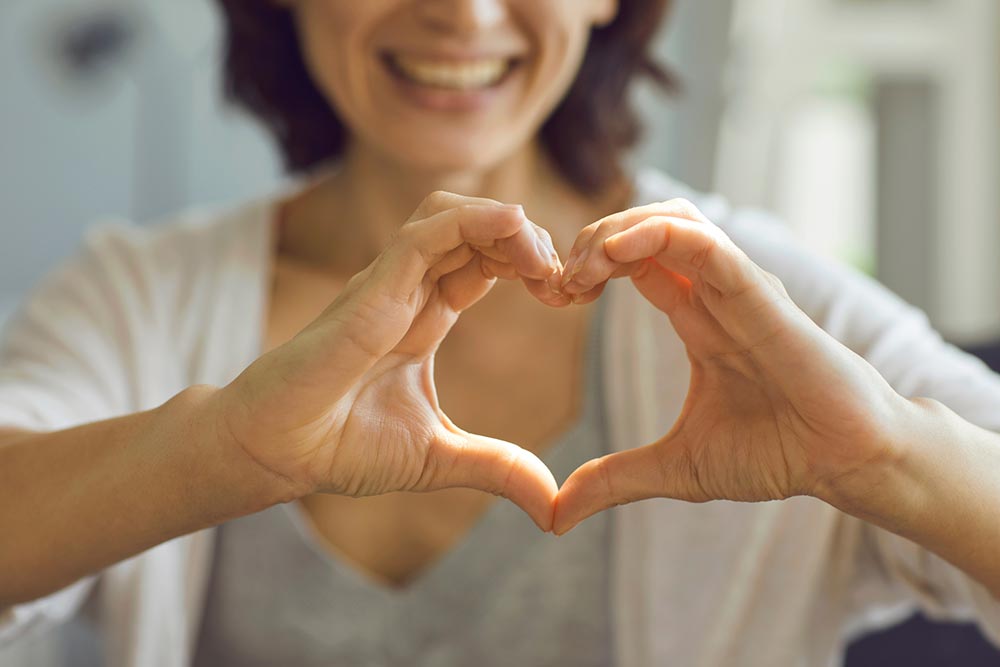 Woman smiling and holding her hands in the shape of a heart