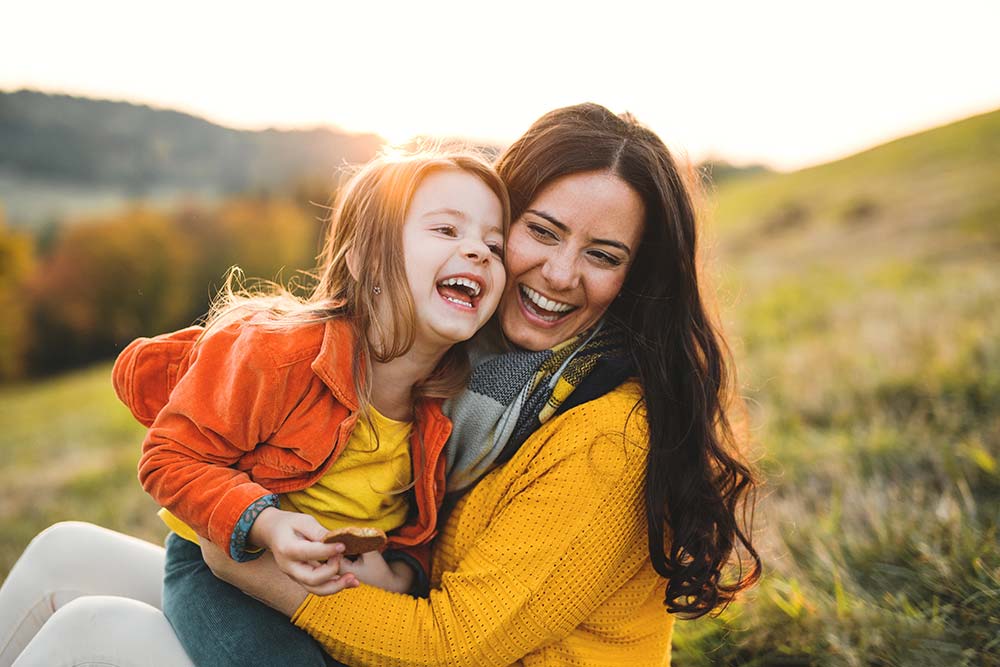 Woman and child laughing on a hillside